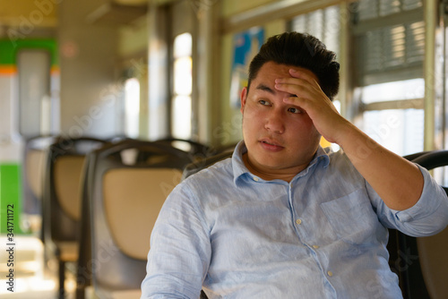 Stressed overweight Asian tourist man feeling hot inside the train