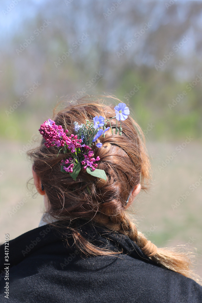 Naklejka premium wildflowers in girl’s hair against the background of nature.