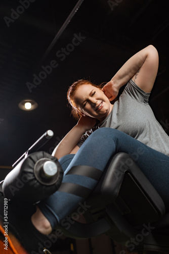 low angle view of purposeful overweight girl doing abs exercise on fitness machine