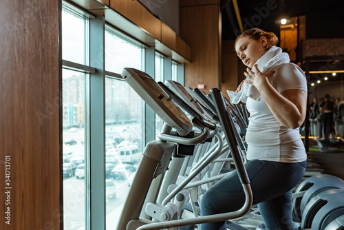 Tablou pe pânză tired overweight girl touching towel while working out on stepper