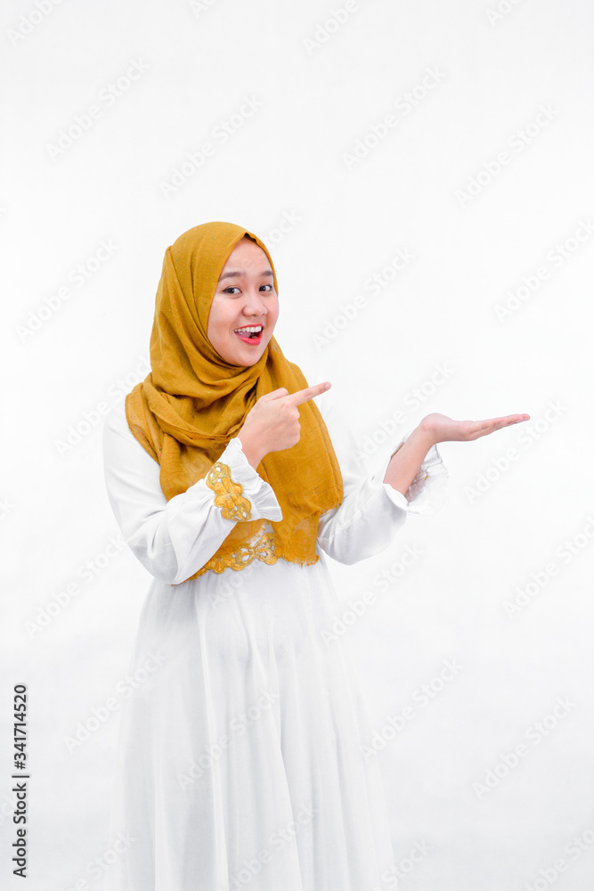 portrait of a asian muslim woman pointing some thing with hand and presenting something on copyspace isolated over white background portrait of a asian muslim woman pointing some thing with hand and presenting something on copyspace isolated over white background