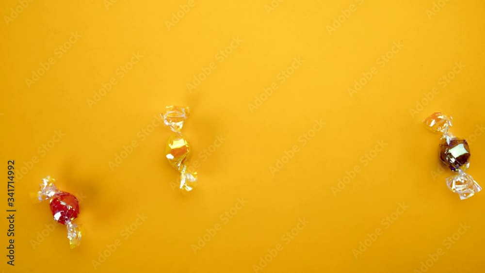 Multicolor candies on yellow background  stop motion animation 4k