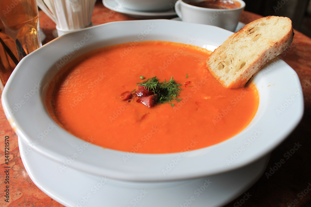 Pumpkin cream - soup with sausages and white bread in a white plate Pumpkin cream - soup with sausages and white bread in a white plate