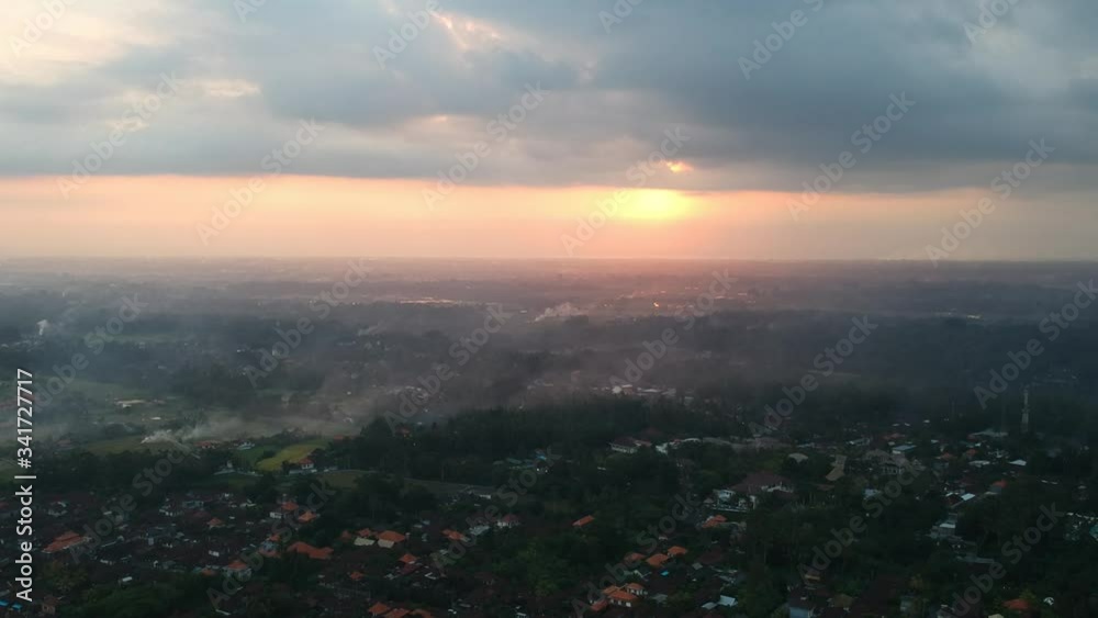 quadrocopter flies over over the jungle of Ubud in Bali, and flies to sunset, the whole sky is in the clouds and the yellow-orange sun is visible, everything is in the haze quadrocopter flies over over the jungle of Ubud in Bali, and flies to sunset, the whole sky is in the clouds and the yellow-orange sun is visible, everything is in the haze