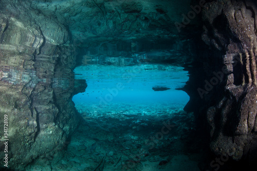 Light seeps into a dark, underwater cavern in the tropical Pacific Ocean. Caves and caverns riddle coral reefs and limestone islands.