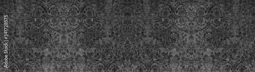 Old dark black anthracite vintage shabby patchwork with flower leaves print motif tiles stone concrete cement wall texture background banner panorama