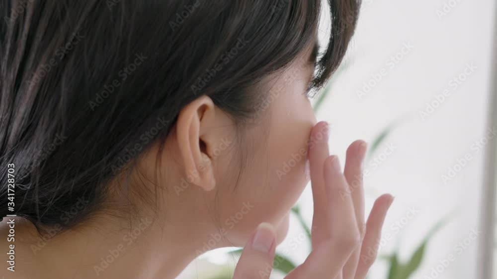 Beautiful young asian woman smiling look at mirror of checking face and skin care cream and cosmetic for rejuvenation and hygiene, beauty girl happy clean facial with lotion and for health. Beautiful young asian woman smiling look at mirror of checking face and skin care cream and cosmetic for rejuvenation and hygiene, beauty girl happy clean facial with lotion and for health.