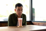 Young Asian man drinking shake at the coffee shop