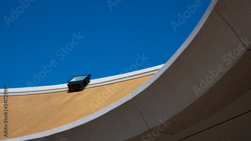 Low angle view of spotlight on top of modern roof in curve pattern against blue clear sky background in sunny day, exterior architecture concept