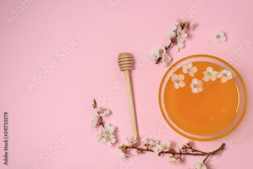 honey in a plate with a spoon and cherry flowers on a pink background. natural ingredient for skin care © Taranova_ksenya