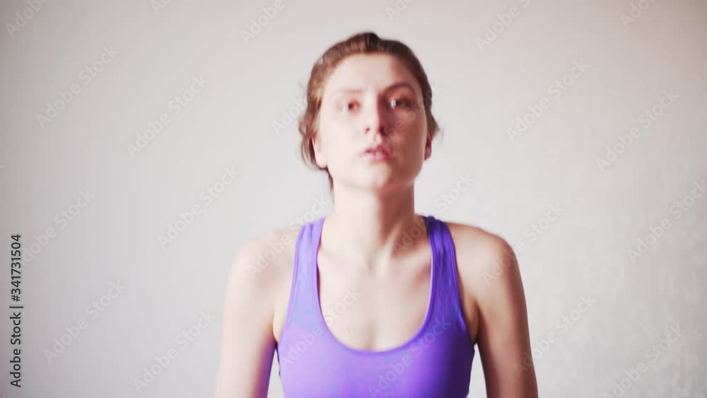Caucasian woman doing squats in front of the camera, online workout. A healthy lifestyle during quarantine. Active beautiful girl is engaged in fitness at home
