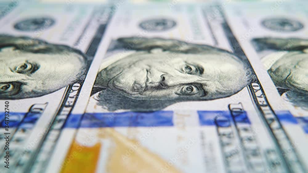 Macro dolly shot of American hundred dollar bills lying in row