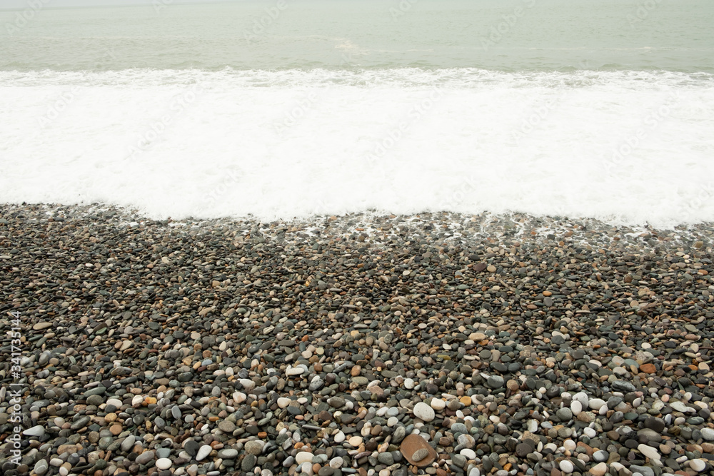 Waves on the beach shore. Shore of rocky pebbles. Mainly cloudy. Day, spring, Georgia. Waves on the beach shore. Shore of rocky pebbles. Mainly cloudy. Day, spring, Georgia.