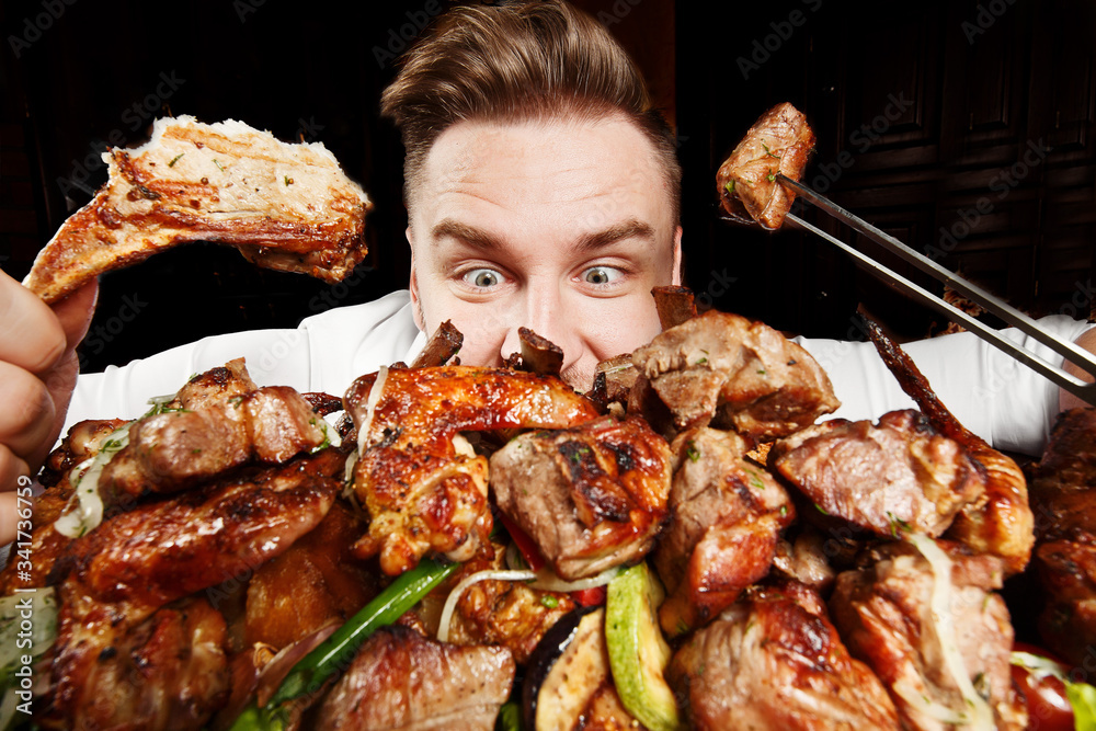 Crazy hungry man eating mix grill meat. Emotional content for restaurant  promo. Cheat day. Meat lover. Lamb chops, chicken tikka, kebab, lamb, beef  steak. Enjoy your food Photos