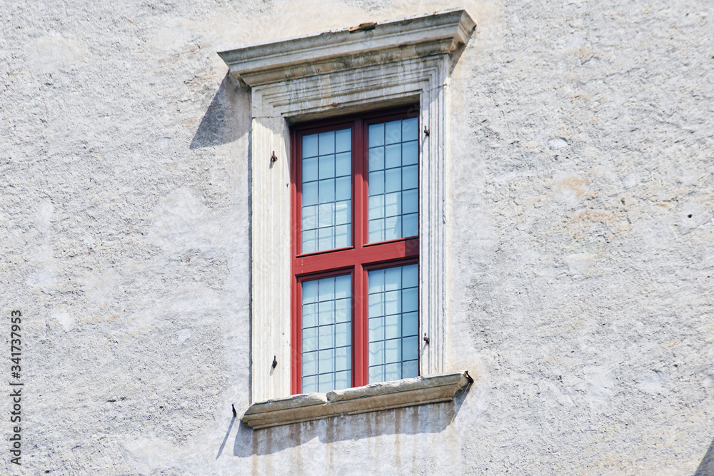Italian window on the old castle wall facade with wooden red color frame Italian window on the old castle wall facade with wooden red color frame