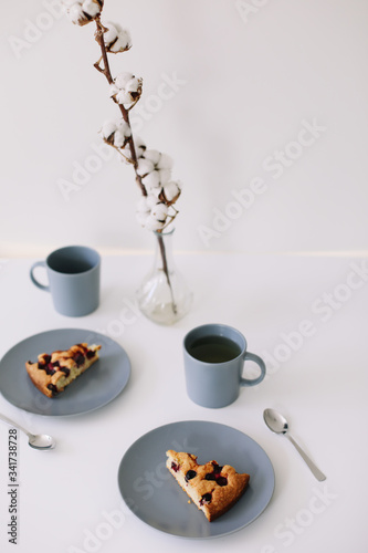Piece of pie on plate with cup of tea on white table. Breakfast with tea and cake. Food photography. Table top photo. Tea time