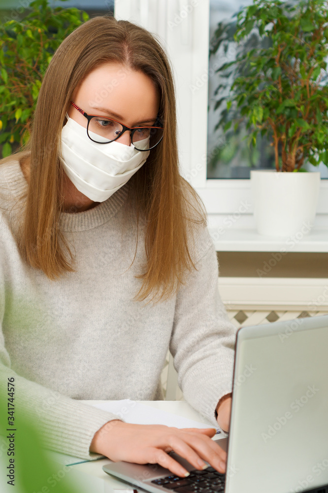 Woman in glasses and mask works from home. Quarantine concept.