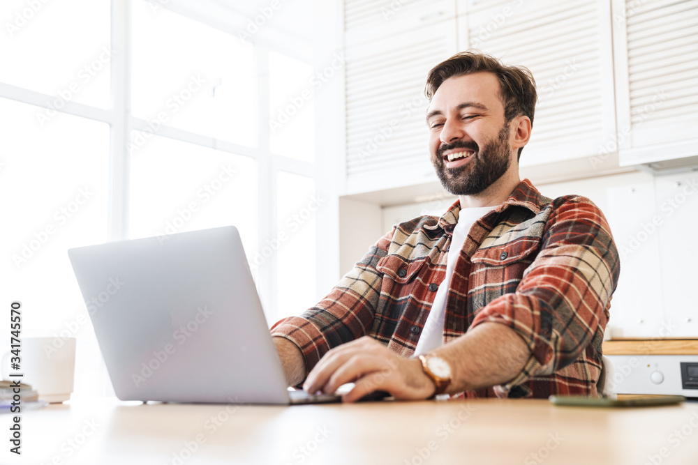 Portrait of man working with laptop and laughing while sitting at table Portrait of man working with laptop and laughing while sitting at table