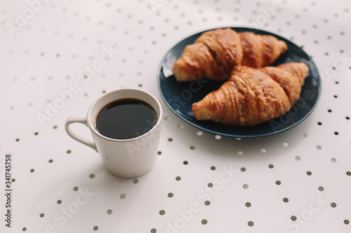 Coffee cup and fresh baked french croissants in blue plate on white background. Breakfast.