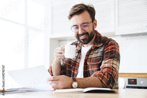 Portrait of young bearded man drinking tea while working at home