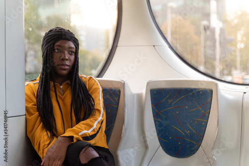 Young black woman sitting alone at public transport during the day, Zagreb, Croatia.