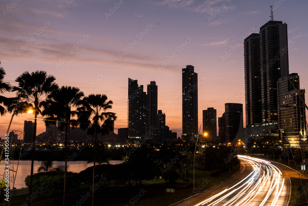 skyline of panama at sunset, palms and the street in motion