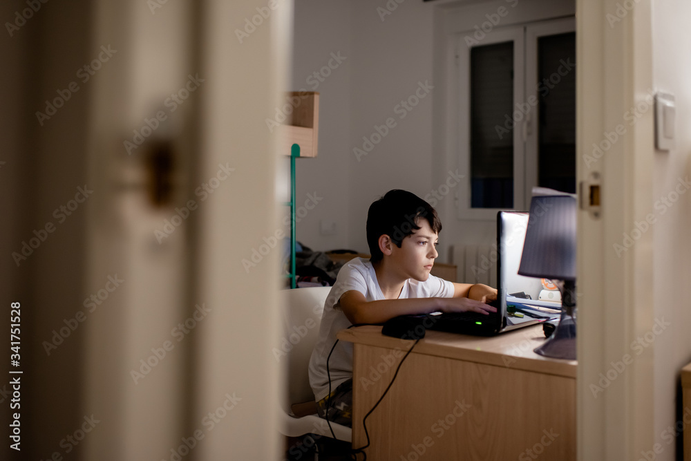 A boy using a laptop in his workspace A boy using a laptop in his workspace