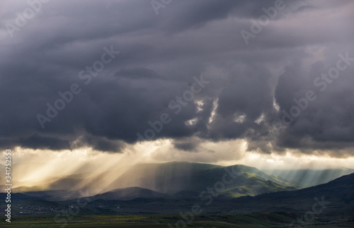 Landscape with rain clouds hills and rays from the sun © Roman