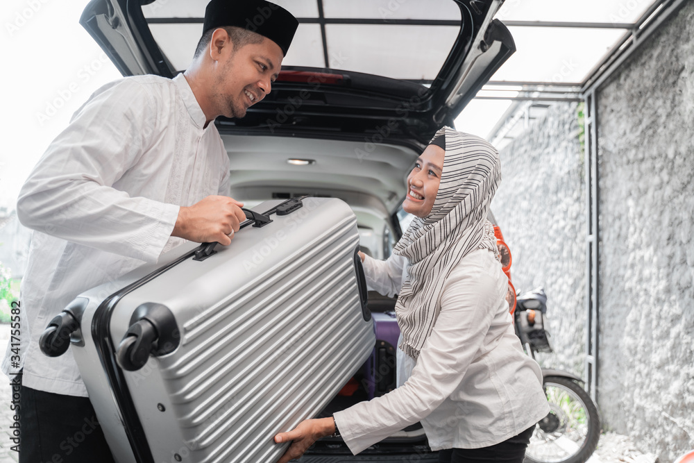 muslim couple packing suitcase in the car trunk for holiday
