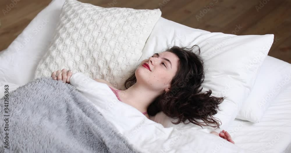Young beautiful curly women waking up fully rested in the morning. Cute girl laying in the bed and smiling in her sleep. Young beautiful curly women waking up fully rested in the morning. Cute girl laying in the bed and smiling in her sleep.