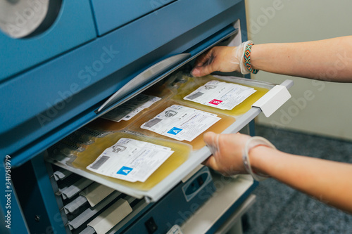 Bags with blood plasma. Medical specialist is checking bags with plasma into at laboratory. Closeup of blood plasma in drips being shaken in machine	 photo