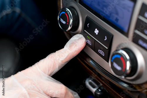a hand in a medical glove presses the air recirculation button in the car photo
