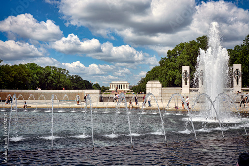 Water splashing from the fountain at the World War II memorial with the Washington Monument in the background in the National Mall in Washington D.C.