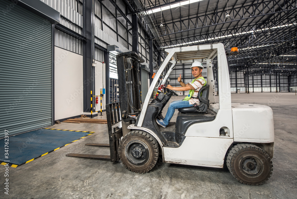 Engineer driving a forklift in a warehouse in logistic zone