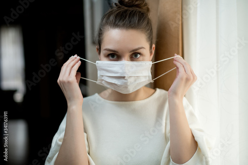 Girl puts on or takes off a medical mask in the hallway at home