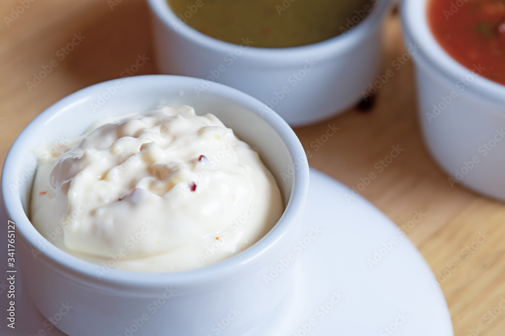 spicy garlic sauce in a white bowl against a background of tkemali sauce and satsebeli spicy garlic sauce in a white bowl against a background of tkemali sauce and satsebeli