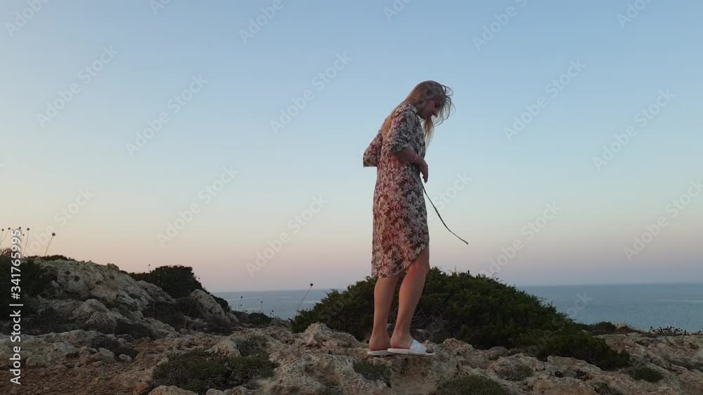 Vacation. Young slim woman sport body in bikini and pareo walking on rocky terrain on a background of blue sea at Cape Greco for sunset Vacation. Young slim woman sport body in bikini and pareo walking on rocky terrain on a background of blue sea at Cape Greco for sunset