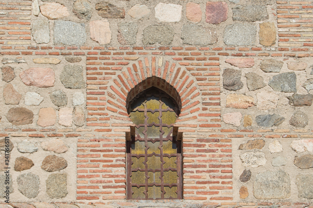 window with pointed horseshoe arch on a stone and brick facade on a building in Spain