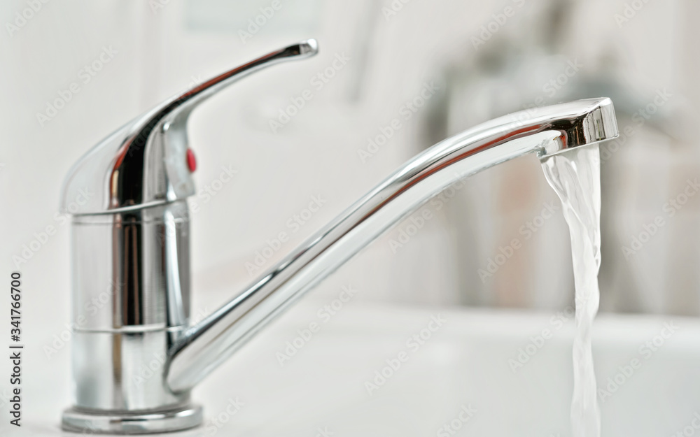 Tap water faucet, with running water, blurred bathroom background, view  from side Stock Photo | Adobe Stock