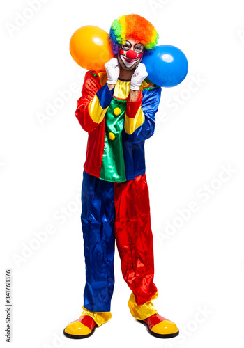 Fotografie, Obraz Full length portrait of a male clown in costume holding bunch of balloons isolat