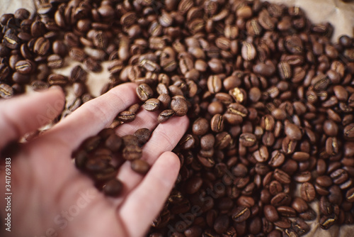 A handful of brown coffee beans in the palm of your hand next to an espresso Cup