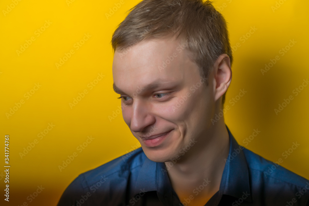 Obraz premium Blond young man smiles sweetly. Isolated yellow background. photo