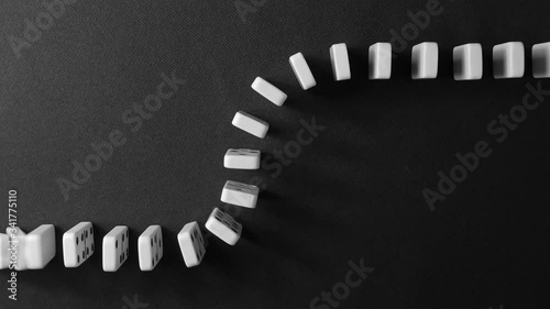 falling white dominoes against a dark background