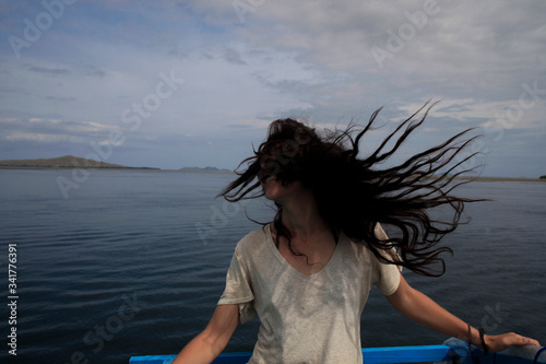 A young long-haired woman on a boat smiling and happy in the sea of flowers, Komodo Indonesia