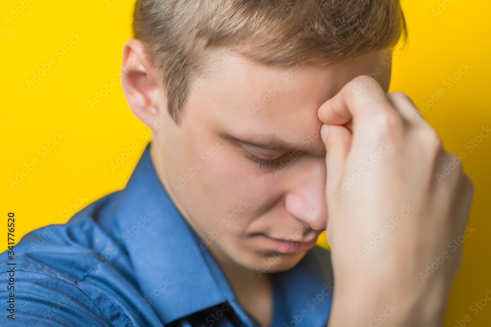 Blond young man. Gesture. Man thinks, looking away. Isolated yellow background. Hand on chin, thinking, on a yellow background Blond young man. Gesture. Man thinks, looking away. Isolated yellow background. Hand on chin, thinking, on a yellow background