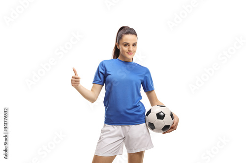 Female football player holding a soccer ball and showing thumbs up