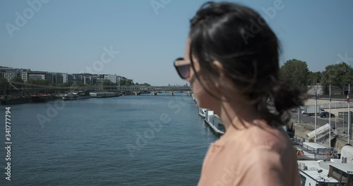 beautiful dark hair Girl with sunglasses walking on a bridge above the Seine river, Paris
