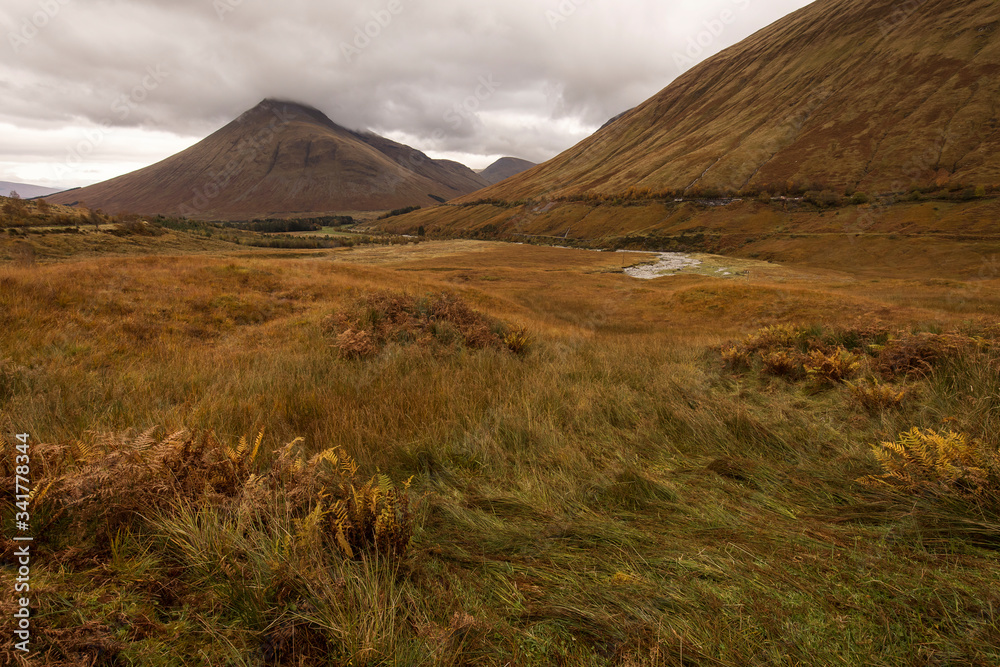 Autumn landscape in Highlands, Scotland, United Kingdom. Beautiful mountains with rainy clouds in background.