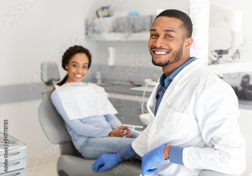 Black dentist doctor and patient in chair smiling at camera