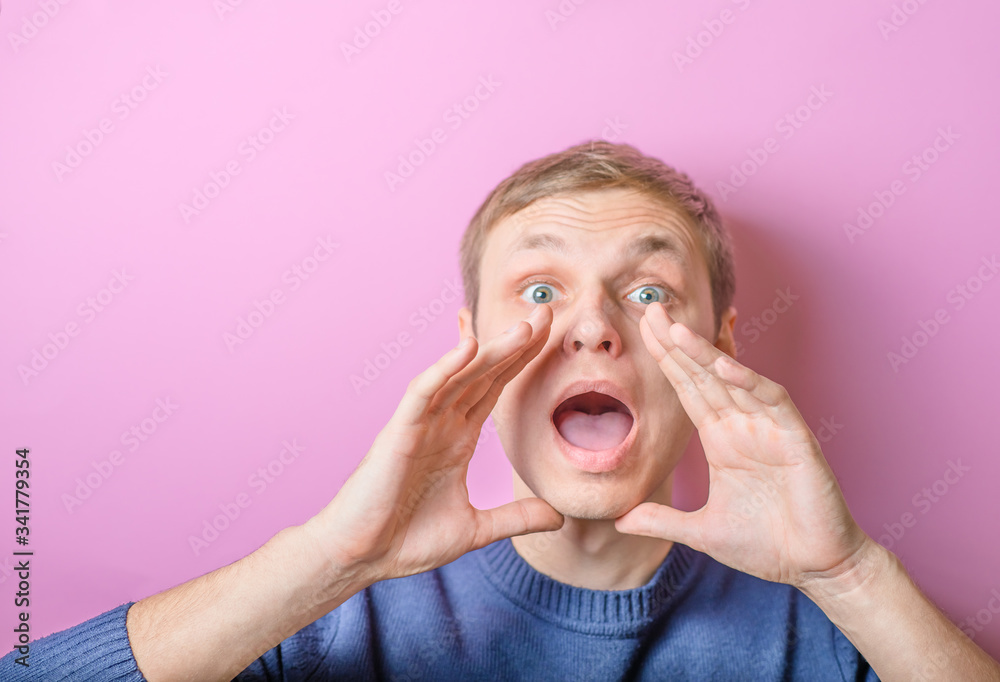Young man calling, screaming. Gesture. On a purple background. Young man calling, screaming. Gesture. On a purple background.